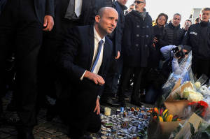 Economy Minister Naftali Bennett lights a candle outside the kosher supermarket in Paris where four Jewish men were murdered by Islamic State-affiliated terrorists. (Photo: Serge Attal/Flash90)
