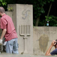 Polish and Jewish youths remove painted swastikas from desecrated gravestones
