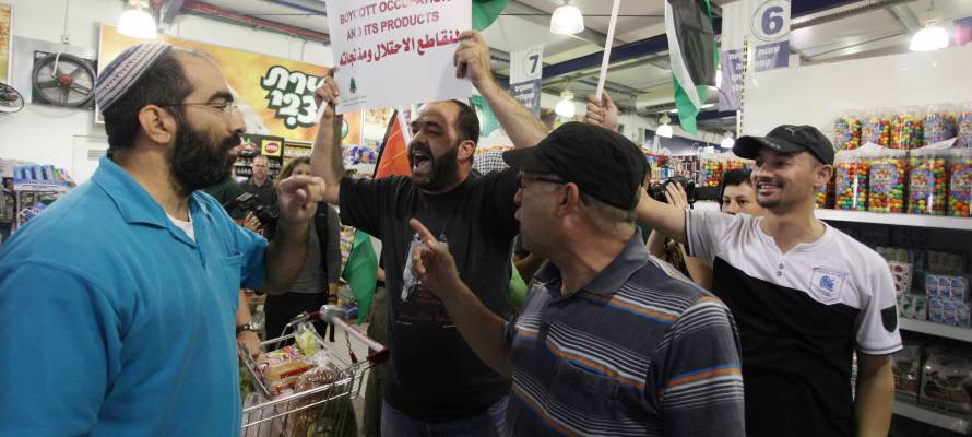 Foreign and Palestinian activists hold Palestinian flags as they march through an Israeli supermarket